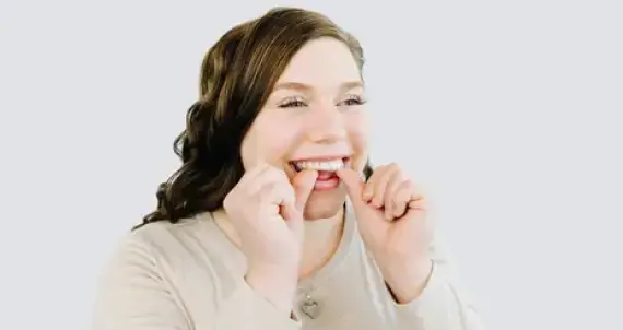 woman putting in retainers smiling